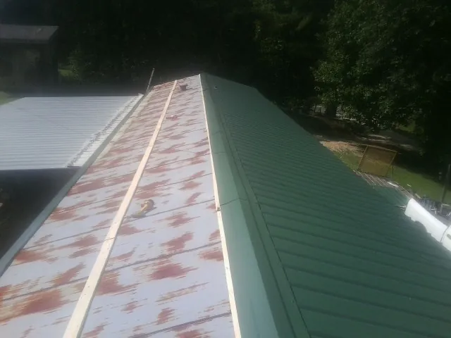 Old rusted panels beside newly installed green metal roofing — Wind Damage Roof Repair by Roofing Brothers in East Lynne