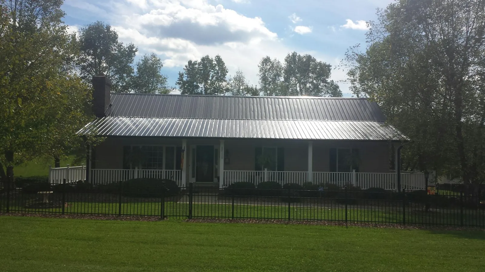 Gray metal roof on a brick ranch with a full width front porch — Gutter Guard Installation work by our crew in East Lynne