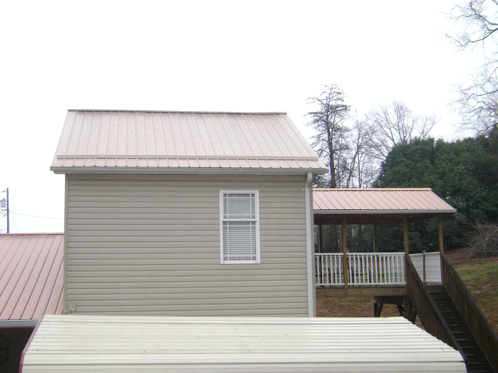 Tan metal roofs on a two story addition and attached porch, from a Roof Replacement job in East Lynne