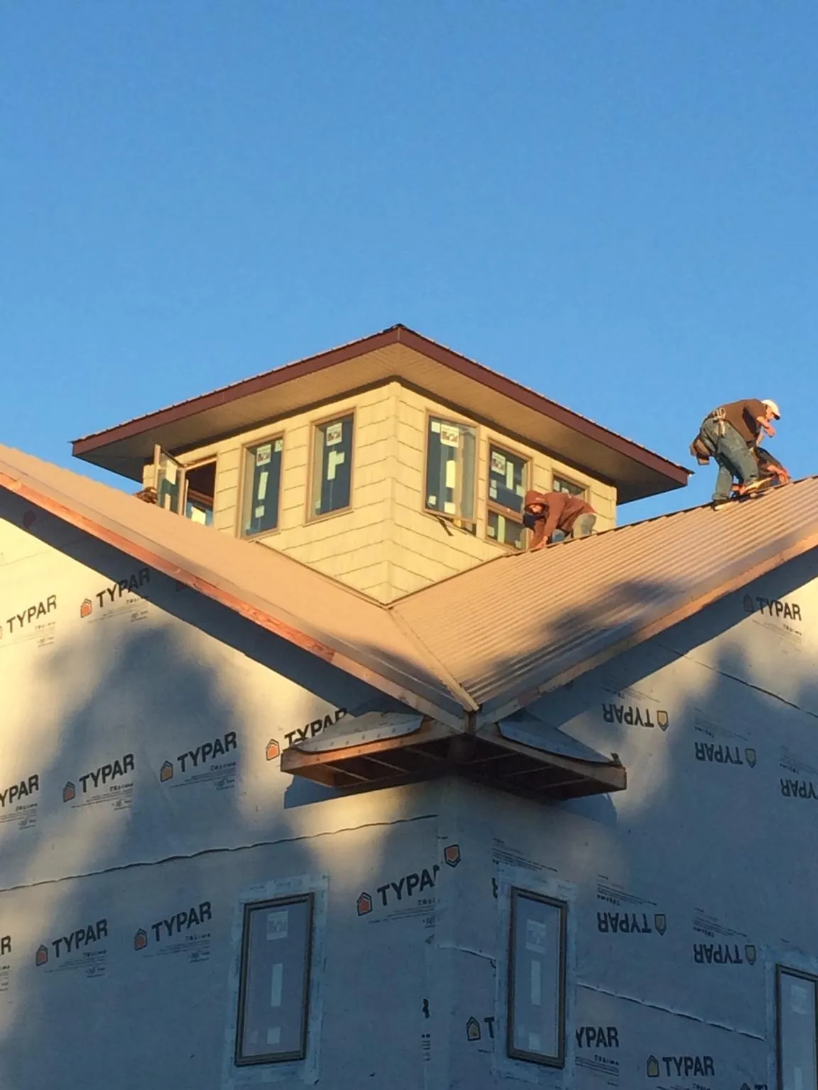 Roofers working around a rooftop cupola on a new metal roof at sunset — Roof Waterproofing in East Lynne by Roofing Brothers